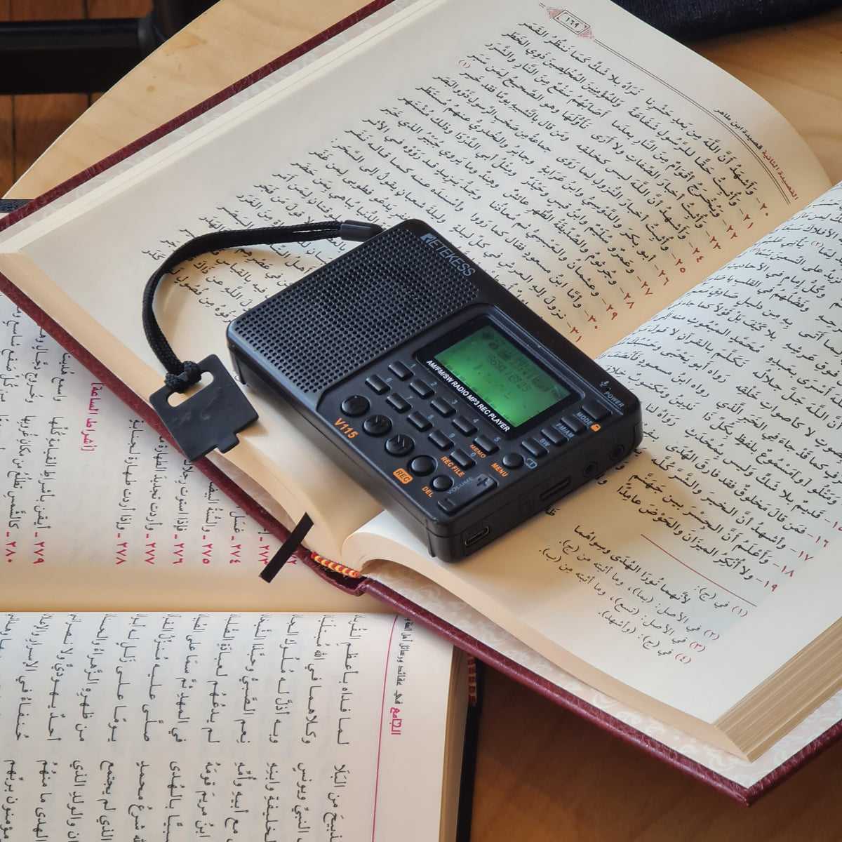 The Qur’ān Radio+ resting on an open book of Arabic poetry